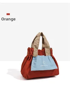 Dettaglio di una borsa in tela arancione con tasca frontale azzurra e motivo a sole ricamato