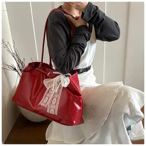 Close-up of a red soft leather tote bag featuring a white lace bow and pearl decoration