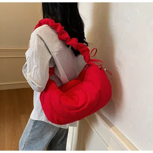 Detail of red quilted dumpling bag showing pleated shoulder strap and nylon fabric