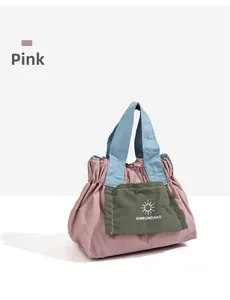Dettaglio della mini borsa in nylon rosa con manici blu e logo verde applicato