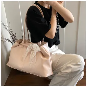 Detail of soft leather tote bag with lace bow and pearl charm for daily commute