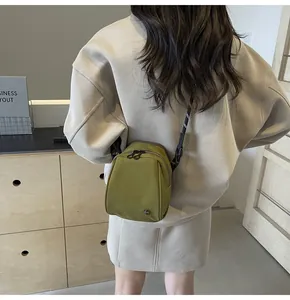 Adjustable shoulder strap detail on olive green nylon crossbody bag worn by a model