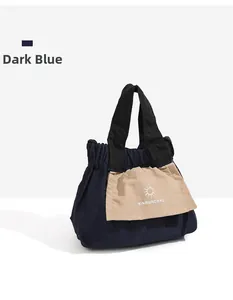 Dettaglio della mini borsa blu scuro con tasca frontale beige e design del logo del marchio