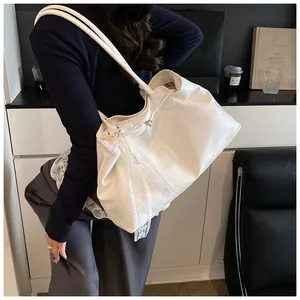 Detailed close-up of white soft leather tote bag with lace bow and pearl chain charm