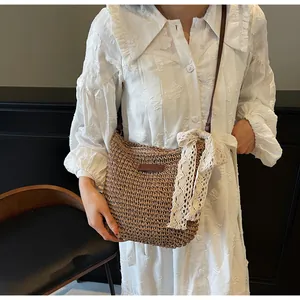 Detail of woven straw crossbody bag with delicate cream lace bow and leather strap