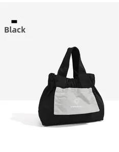 Dettaglio della borsa in tela nera con chiusura a coulisse e logo sole sulla tasca
