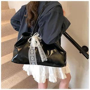 Detail of black glossy leather tote bag with lace bow and pearls on model
