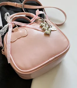 Pink bowling bag detail featuring plaid ribbon, lace bow, and heart metal pendants