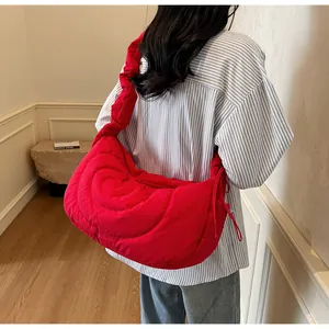 Detail of red quilted crescent bag showing wavy stitching and ruffled shoulder strap