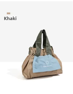 Dettaglio della mini borsa tote kaki con tasca celeste e manici verdi