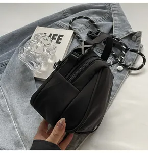 Close-up of black shell crossbody bag with woven rope strap on denim jacket