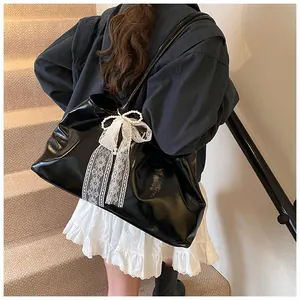 Detail of black glossy faux leather tote bag with white lace bow and pearl charm
