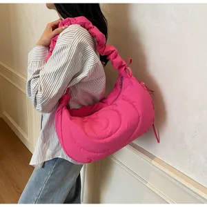 Detail of rose pink quilted hobo bag featuring ruffled straps and spiral stitching