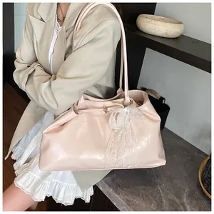 Close-up of pink faux leather tote bag featuring a decorative white lace bow charm detail