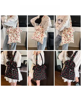 Detail of floral tote bag featuring red cherry patterns and large chiffon ruffle edges