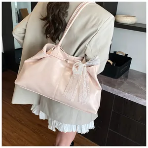 Pale pink soft leather tote bag with lace bow and pearl charm shown on model shoulder