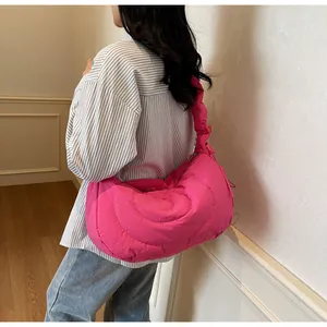 Detail of bright pink quilted half-moon bag featuring pleated handle and puffy texture