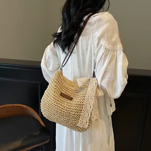Straw crossbody bucket bag with beige lace bow and slim shoulder strap for beach vacation