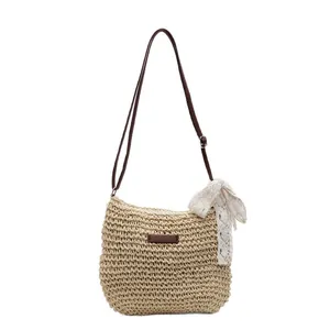 Handwoven straw bucket bag with brown leather strap and white lace bow for summer beach