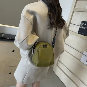 Olive green shell-shaped crossbody bag with dual zippers and woven strap on model