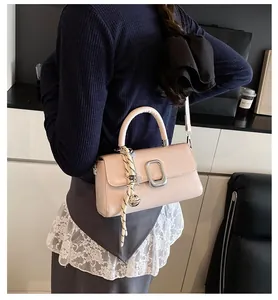 Detail of a beige vintage tote bag with silver buckle and braided bell charm