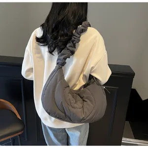 Detail of grey quilted crescent bag showing pleated strap and puffer nylon texture