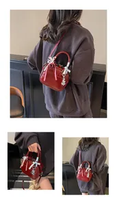 Detail of red patent leather mini bowling bag with decorative ribbons and silver charm