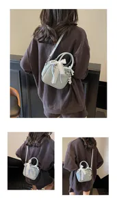 Detailed view of light blue bowling bag with white lace bow and heart-shaped pendant detail
