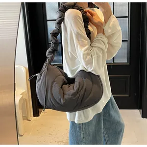 Detail of dark grey quilted crescent bag with ruffled strap shown on shoulder