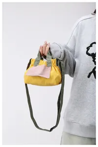 Dettaglio della mini borsa in tela con corpo giallo, tasca rosa e lacci verde militare