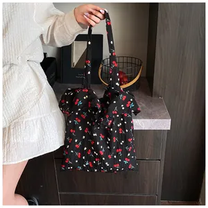 Detail of black mesh tote bag featuring cherry floral print and elegant ruffle trim edges