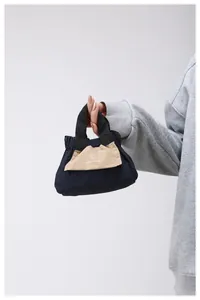Dettaglio della mini borsa a secchiello con logo sole e design a colori contrastanti