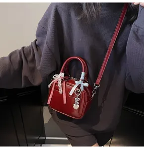Detail of dark red patent leather bowling bag with cute bows and a silver bear charm