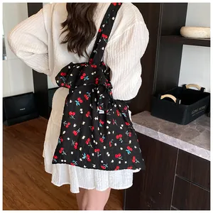Detailed view of black mesh tote bag with red cherry print and oversized shoulder bow