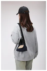 Dettaglio mini borsa a tracolla in nylon blu navy con patta beige indossata dalla modella