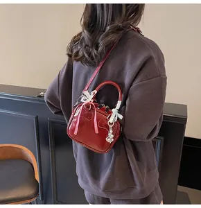 Close-up of a glossy red bowling bag with checkered ribbons and silver heart pendant