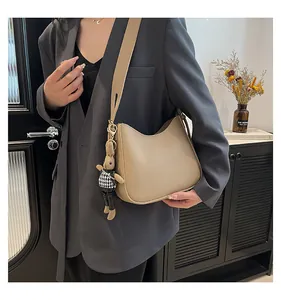 Detail of light khaki leather bucket bag with pebble texture and cute rabbit charm accessory