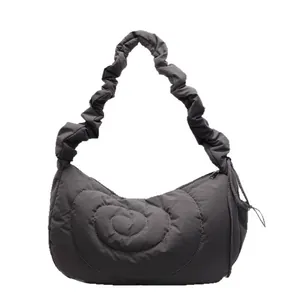 Dark gray quilted puffer bag with spiral stitching and scrunchie shoulder strap on white base