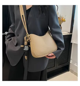 Detail view of khaki crescent bucket bag with lychee texture and cute rabbit charm