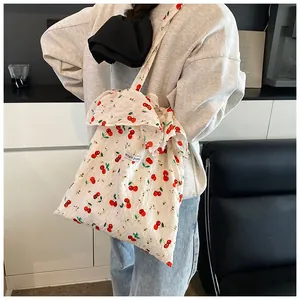 Detail of floral cherry print tote bag with ruffled edges worn as a crossbody bag