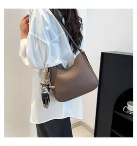 Detail of dark brown lychee leather hobo bag with a cute houndstooth bunny charm
