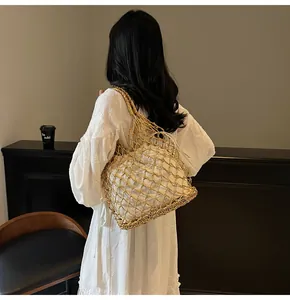 Detalle del bolso de hombro de tejido metálico dorado con bolsa interior blanca con cordón