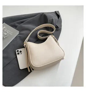 Detail of cream pebbled leather texture and adjustable gold hardware on the shoulder bag