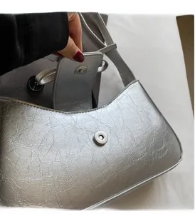 Detail of silver metallic handbag with pleated texture and magnetic buckle closure
