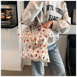 Detail of white mesh tote bag featuring red cherry prints and ruffled chiffon edge trim