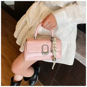 Detail of pink faux leather bag with silver buckle and decorative white silk scarf