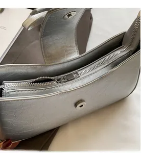 Close-up of silver pleated faux leather texture with metallic zipper and magnetic buckle detail