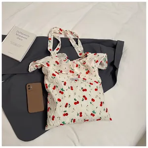 Detail of floral cherry print tote bag with elegant ruffled edges and brand logo tag