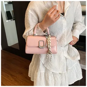 Close-up of pink patent leather handbag with silver hardware and woven rope charm detail