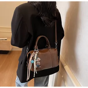Detail of caramel brown Boston bag with embossed lettering and cute bear charm